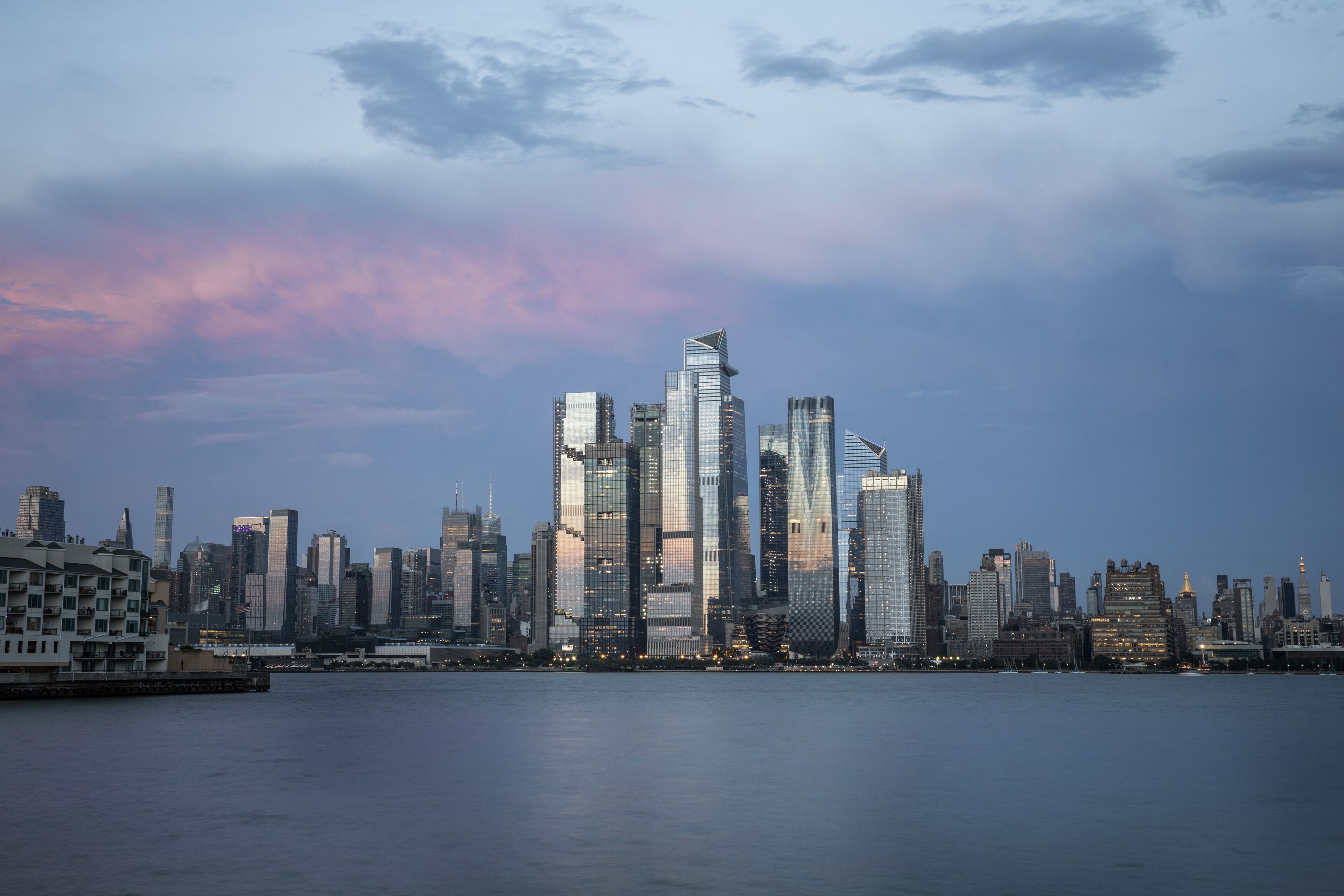 A city skyline with modern skyscrapers and a body of water in the foreground.