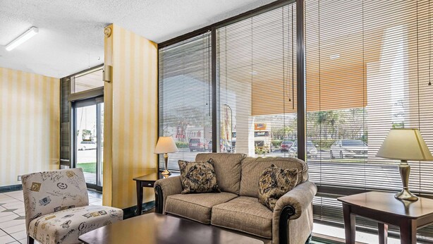 Habitación de hotel con sofá, sillón y una mesita de centro. Hay dos lámparas sobre mesitas auxiliares.