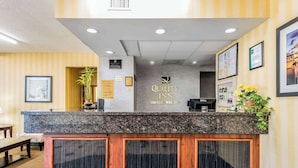 Un área de recepción con mostrador de mármol, certificados enmarcados y el logotipo de Quality Inn by Choice Hotels.