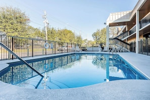 Enjoy a refreshing swim in the pool surrounded by lush greenery and a modern building with a flat roof.