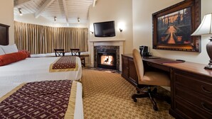 A hotel room with a bed, a desk, a fireplace, a TV, and a painting. - Victorian Inn (Monterey)