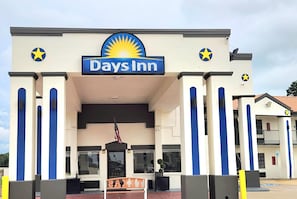 Days Inn -hotelli, jonka edessÀ on suuri kyltti, lippu ja penkki.