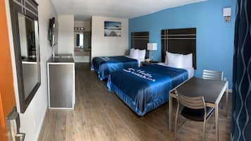 A hotel room with two beds, a desk, and a chair.