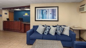 A reception area with a blue sofa, a small table, and a framed abstract painting on the wall. - Days Inn by Wyndham Rockford I-90 Casino District (Rockford)