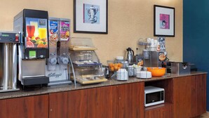 A hotel breakfast area with a coffee machine, cereal dispensers, a microwave, and a fruit bowl. - Days Inn by Wyndham Rockford I-90 Casino District (Rockford)