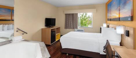 Habitación de hotel con una cama grande, baño independiente con bañera, televisión y ventana con cortinas.