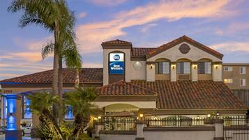 A hotel with a Best Western sign, palm trees, and a tiled roof.