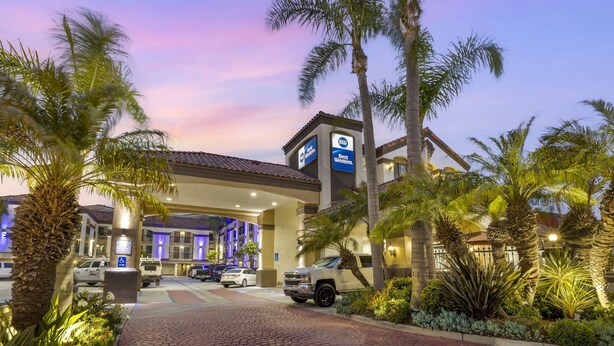 A hotel entrance with a Best Western sign, palm trees, and a brick pathway leading to the parking area. - Best Western Redondo Beach Galleria Hotel - Beach City LA (Redondo Beach)