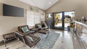 A spacious living area with leather sofas, a flat-screen TV, and a large window offering a view of the outdoors. - Best Western Redondo Beach Galleria Hotel - Beach City LA (Redondo Beach)