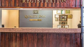 A registration desk at Quality Inn with a wooden panel design and framed awards on the wall.