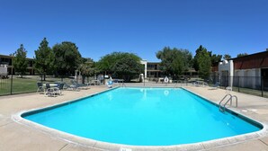 A rectangular swimming pool with a clear blue water, surrounded by a concrete deck.