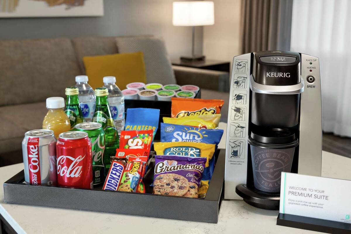 A coffee maker and a tray with snacks and drinks.