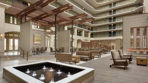 A spacious atrium with a central water feature, multiple seating areas, and a modern architectural design with exposed beams and balconies. - Embassy Suites by Hilton Milpitas Silicon Valley (Milpitas)