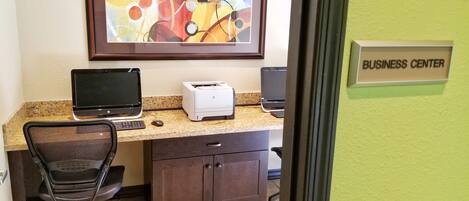 Centro de negocios con una computadora de escritorio, impresora y una silla de oficina.