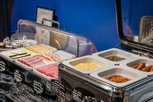 A buffet with various food items including meats, cheeses, and sauces.