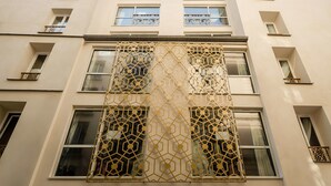 A multi-story building with a geometric patterned facade, multiple balconies, and a clear sky. - Archétype Etoile (Paris)