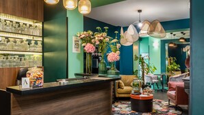A modern bar area with a wooden counter, shelves of glassware, and a variety of flowers. - Archétype Etoile (Paris)