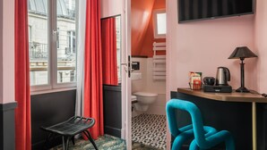 A compact hotel room with a balcony, a small kitchenette, a bathroom, and a TV mounted on the wall. - Archétype Etoile (Paris)