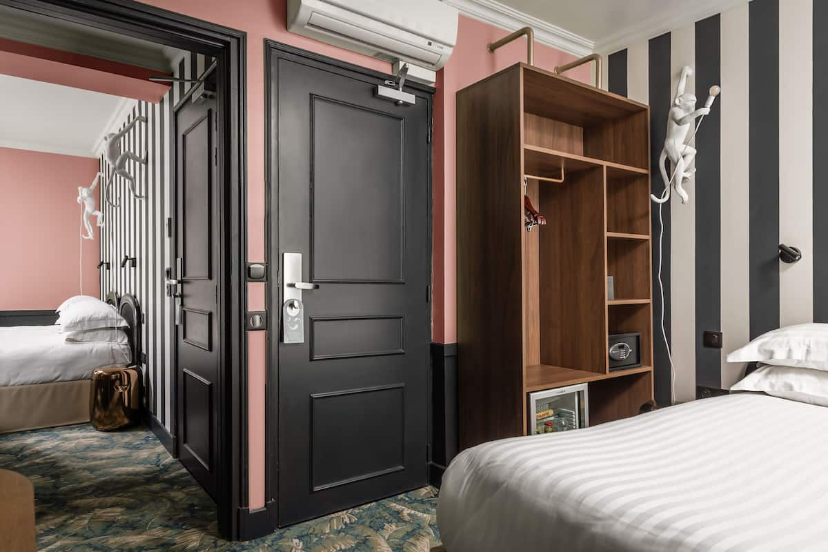 Quarto de hotel com cama, guarda-roupa, escrivaninha e cadeira.