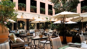 An outdoor dining area with tables and chairs, surrounded by lush greenery and potted plants. - MJ's (Malmö)
