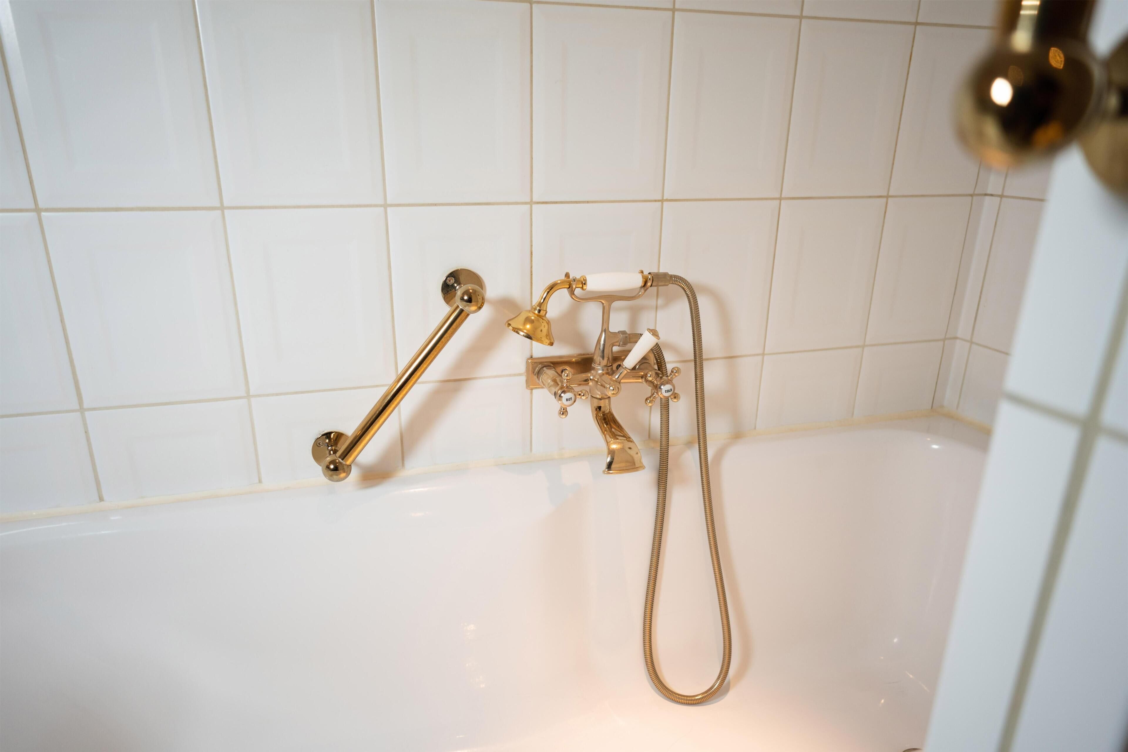 Een bad met een handdouche en een handmixer.