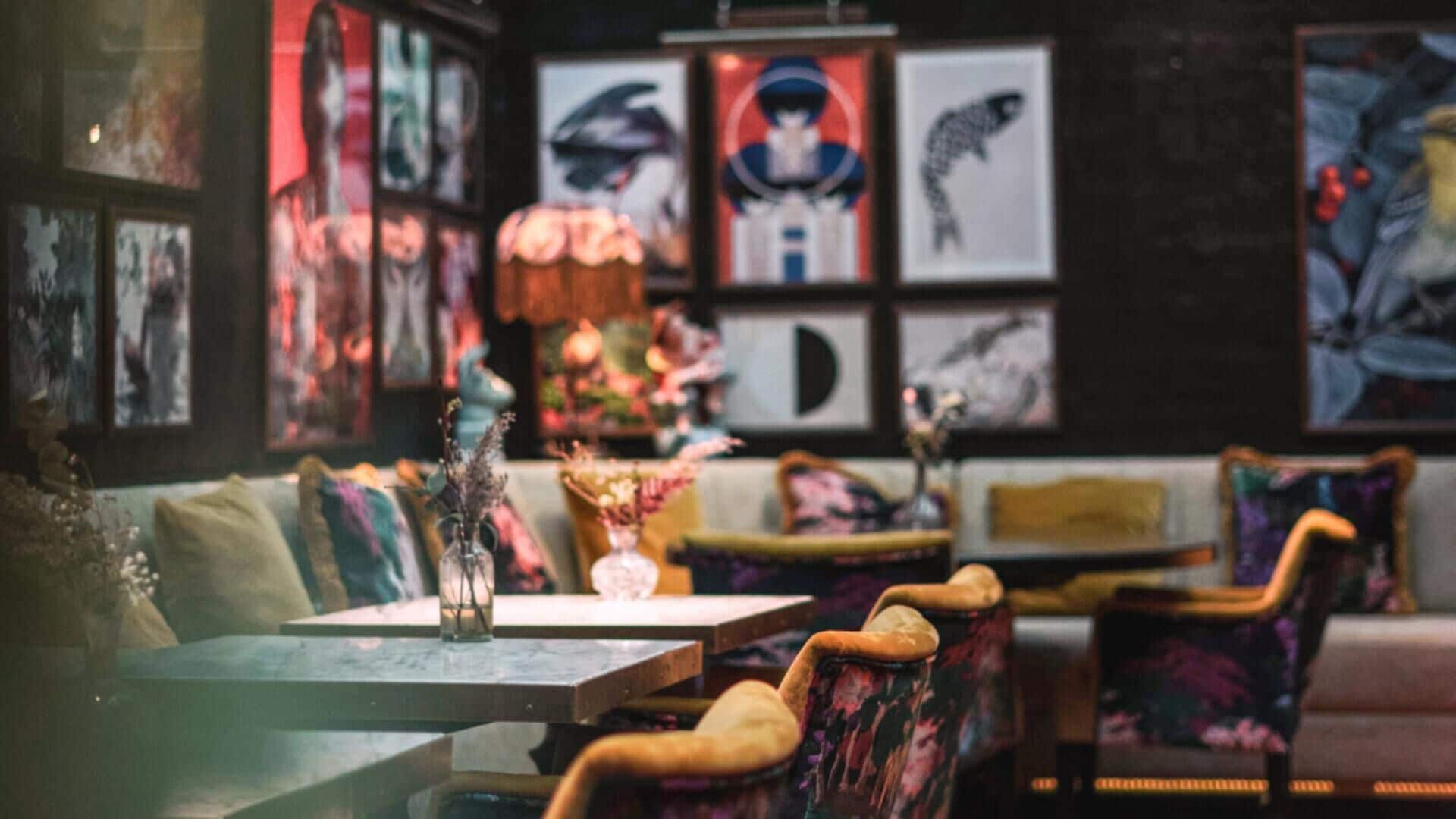 Un acogedor interior de restaurante con cabinas y mesas, decorado con obras de arte enmarcadas y arreglos florales.