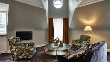 A living room with a round coffee table, two armchairs, a sofa, a TV, and a lamp.