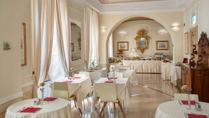 Une salle à manger élégante avec des tables rondes, des nappes blanches et des serviettes rouges.
