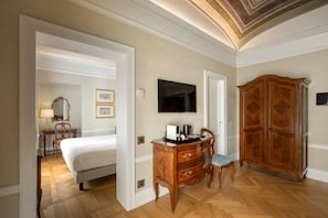 A hotel room with a bed, wooden dresser, television, and a large armoire.