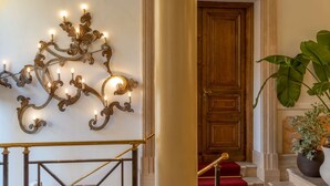Un grand escalier orné d’un luminaire décoratif fixé au mur et d’une porte en bois.
