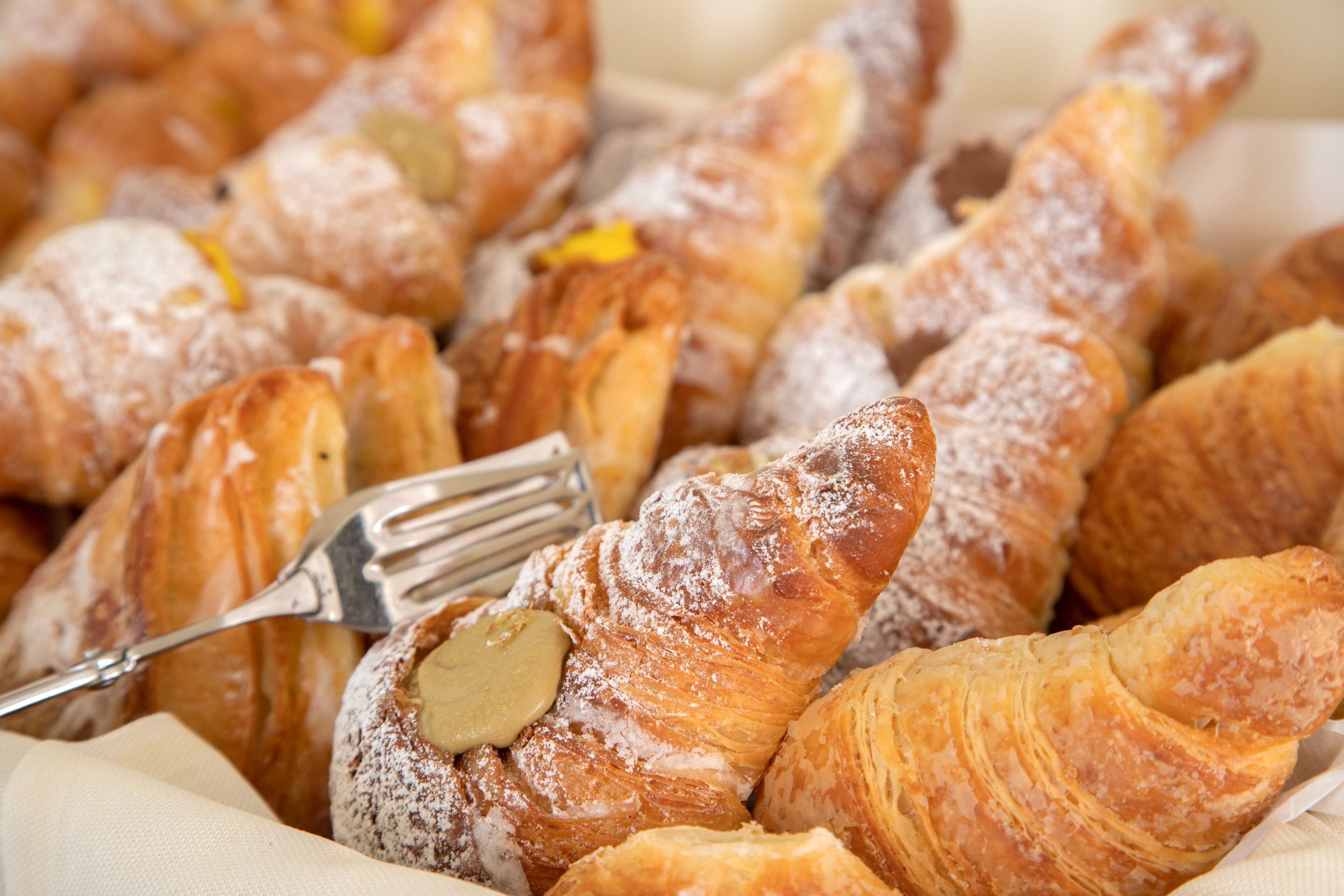 A variety of pastries, including croissants and a pastry with a filling, arranged on a tray.
