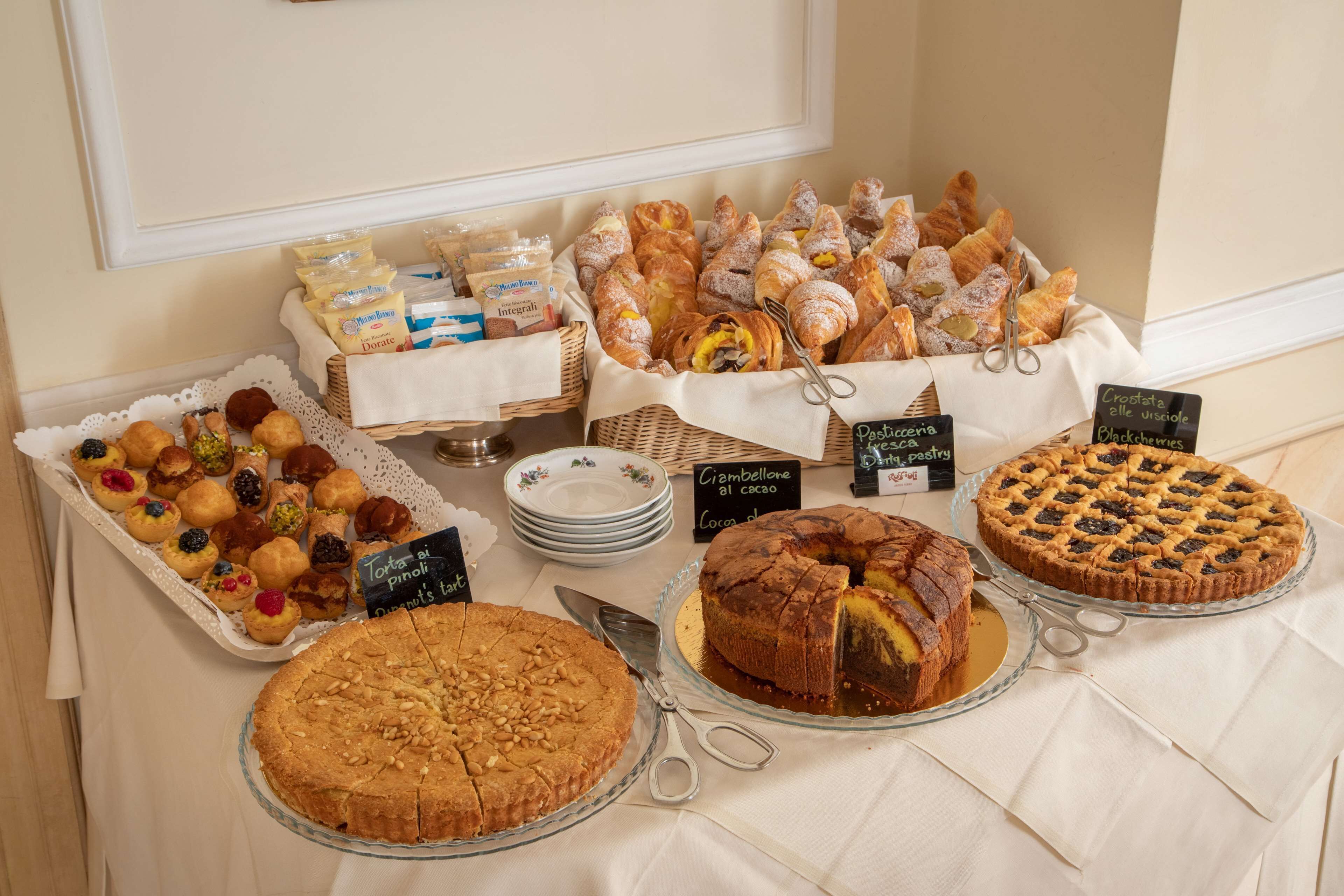 A buffet table with various pastries, cakes, and bread.