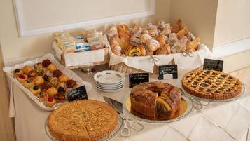 A buffet table with various pastries, cakes, and bread.
