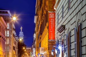A historic street with a prominent Hotel Canada sign, classic architecture, and a statue in the background.