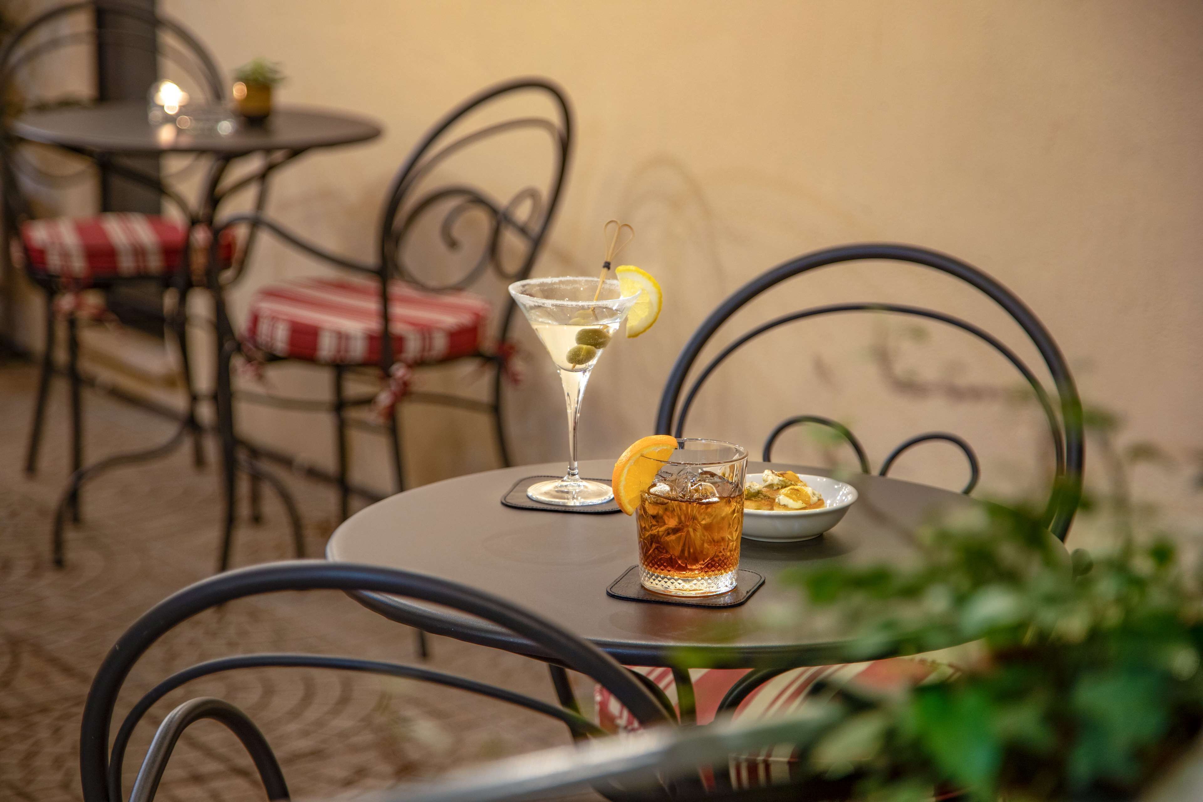 A table with a martini glass, a bowl of snacks, and a plate of food.