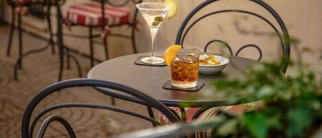 A table with a martini glass, a bowl of snacks, and a plate of food.
