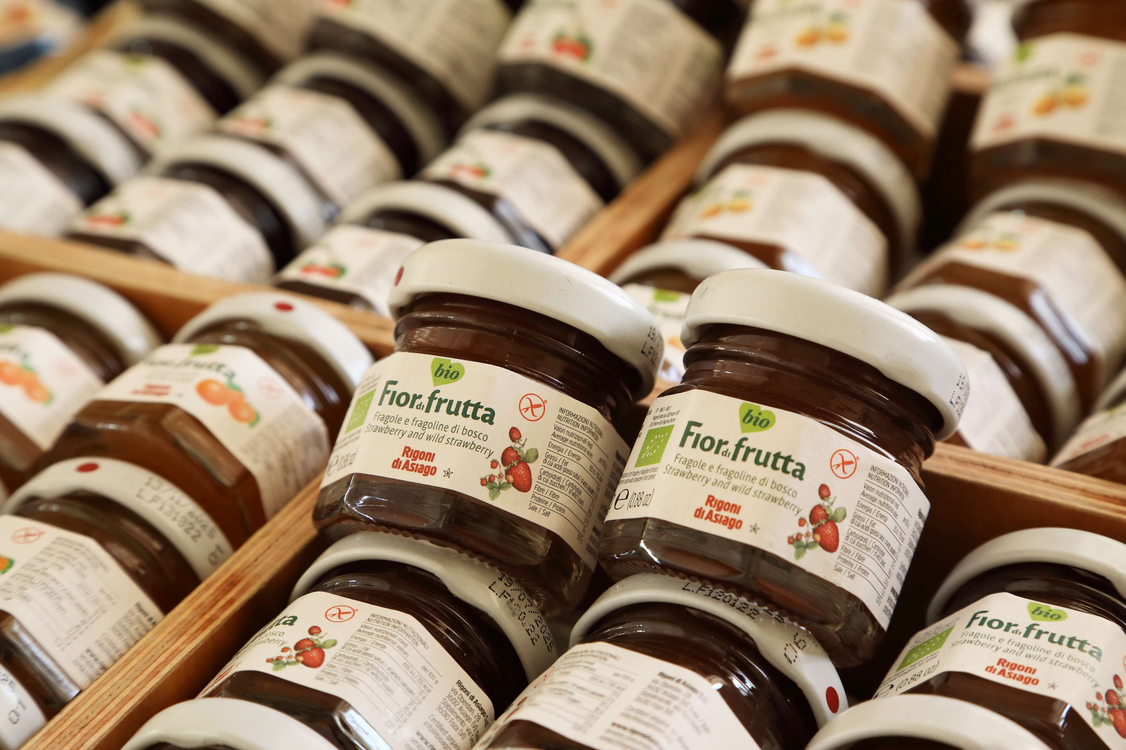 Plusieurs pots de confiture de fraises Fior.fruutta, rangés dans des caisses en bois.
