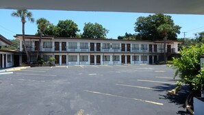 Un motel con una estructura de dos pisos, varias habitaciones y un amplio estacionamiento.