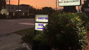 Atardecer en un motel con letreros que indican nuevas tarifas y administración.