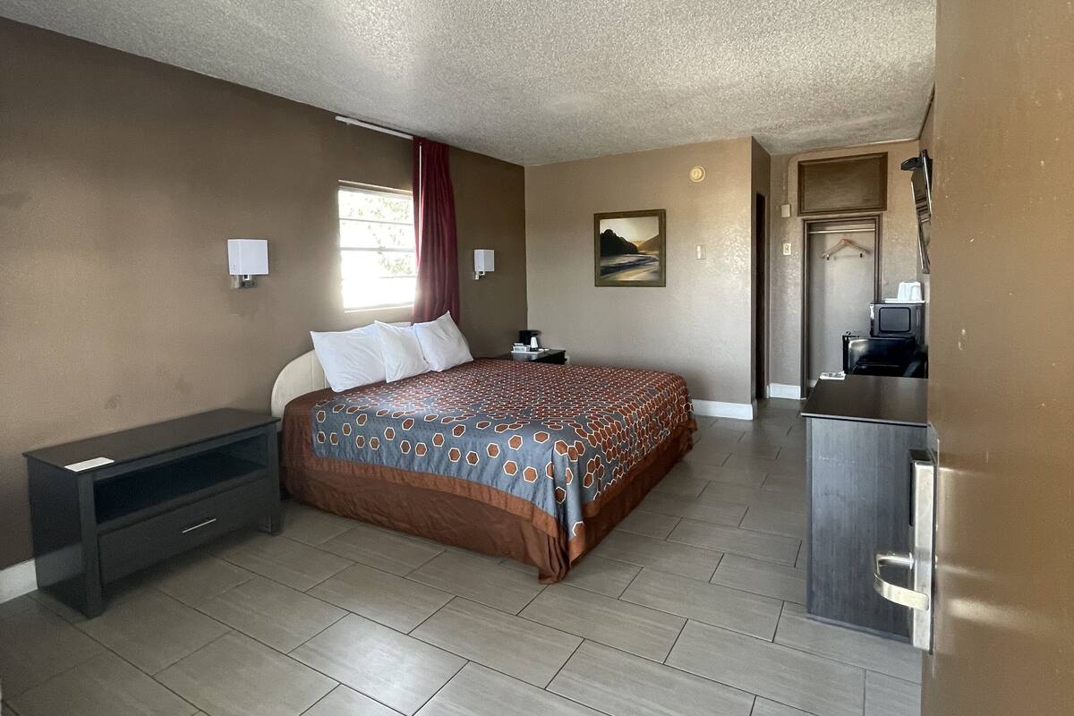 A bedroom with a bed, bedside table, and a dresser.