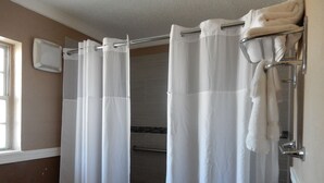 Un baño con cortina de ducha, toallero y calentador de pared.