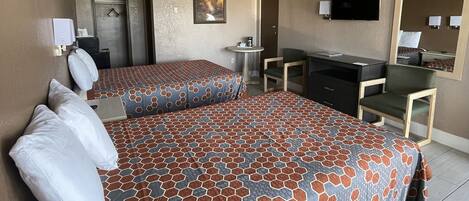 A hotel room with two beds, a desk, a chair, a television, and a mirror.
