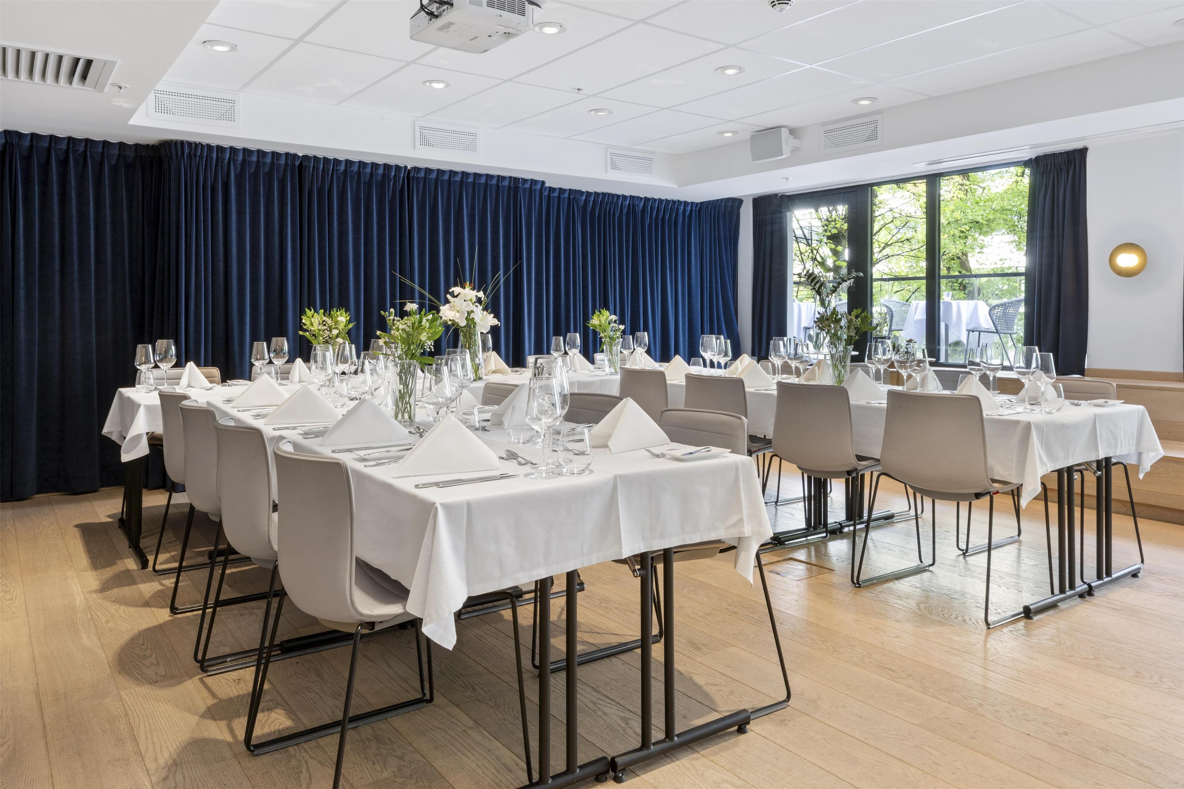A conference room with multiple tables set for dining, equipped with chairs, tables, and glassware.