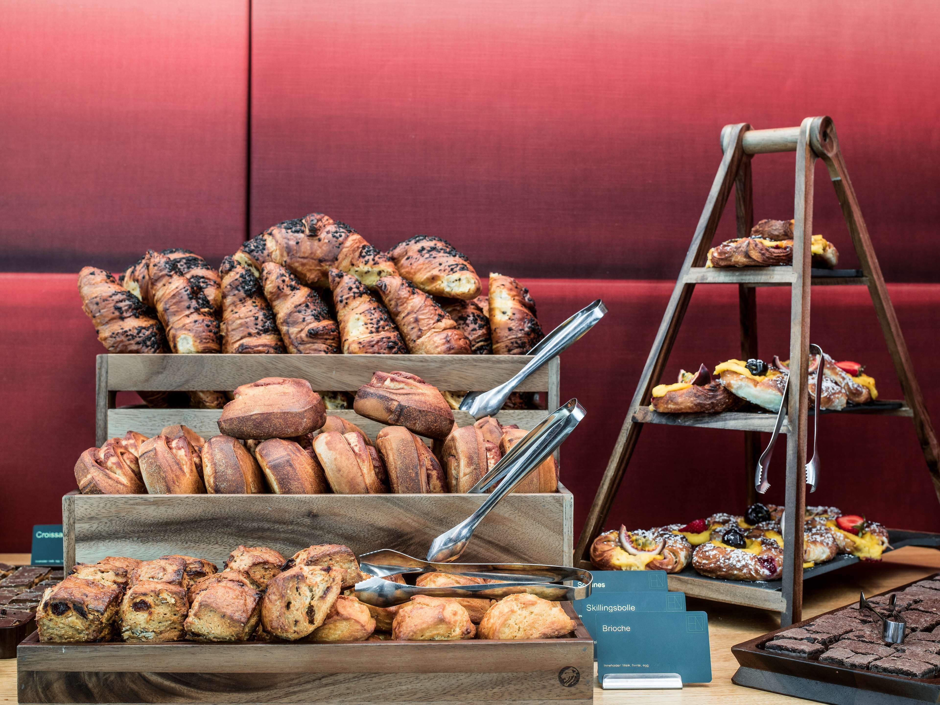 A variety of baked goods displayed on wooden stands and a tiered serving tray.