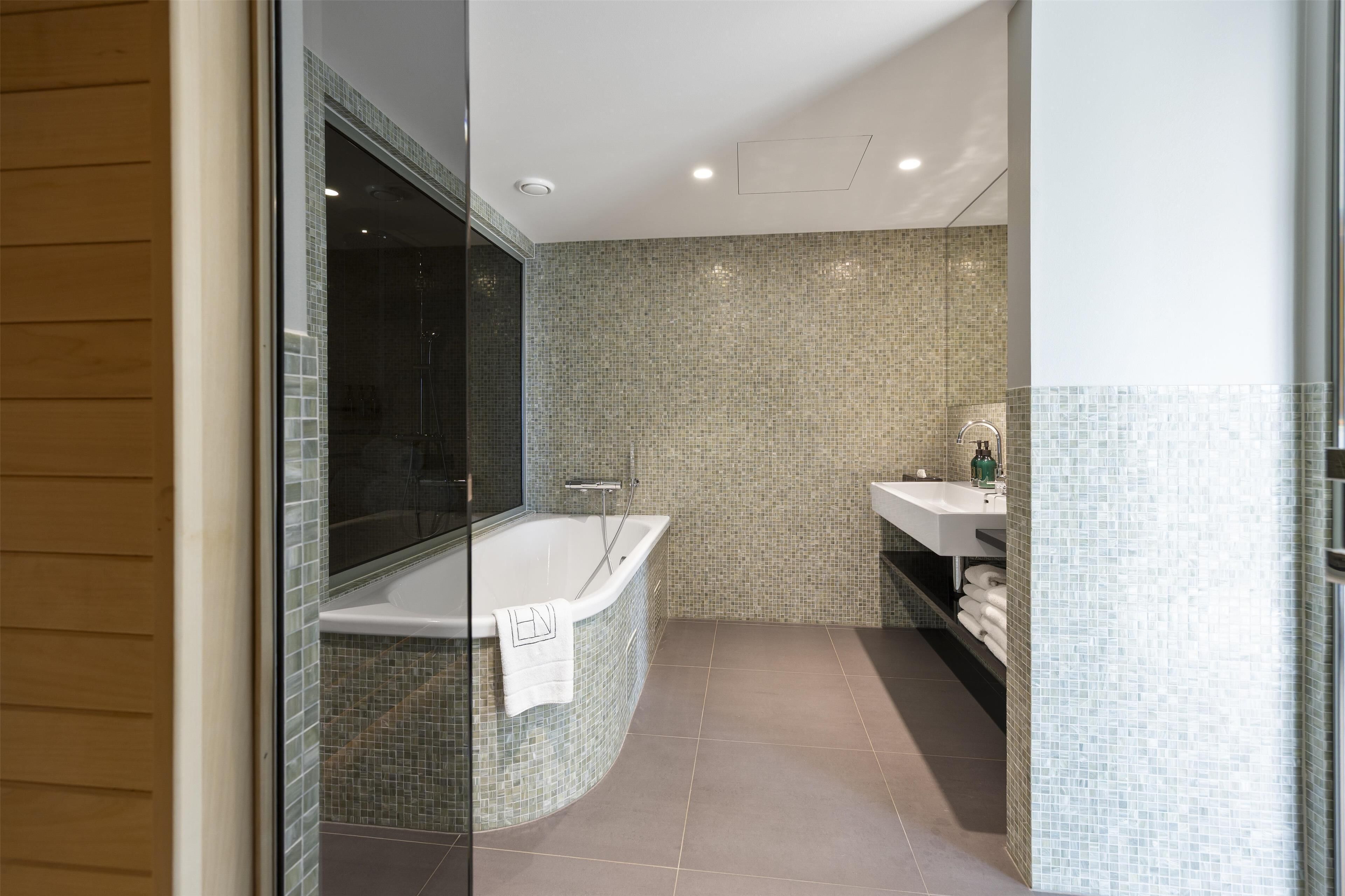 A modern bathroom with a freestanding bathtub, a glass shower enclosure, and a tiled backsplash.
