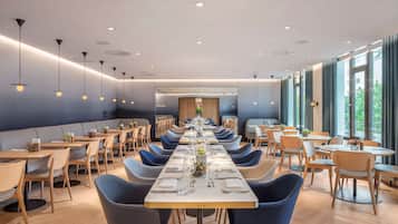 Un comedor moderno con mesas largas, sillas azules e iluminación colgante.