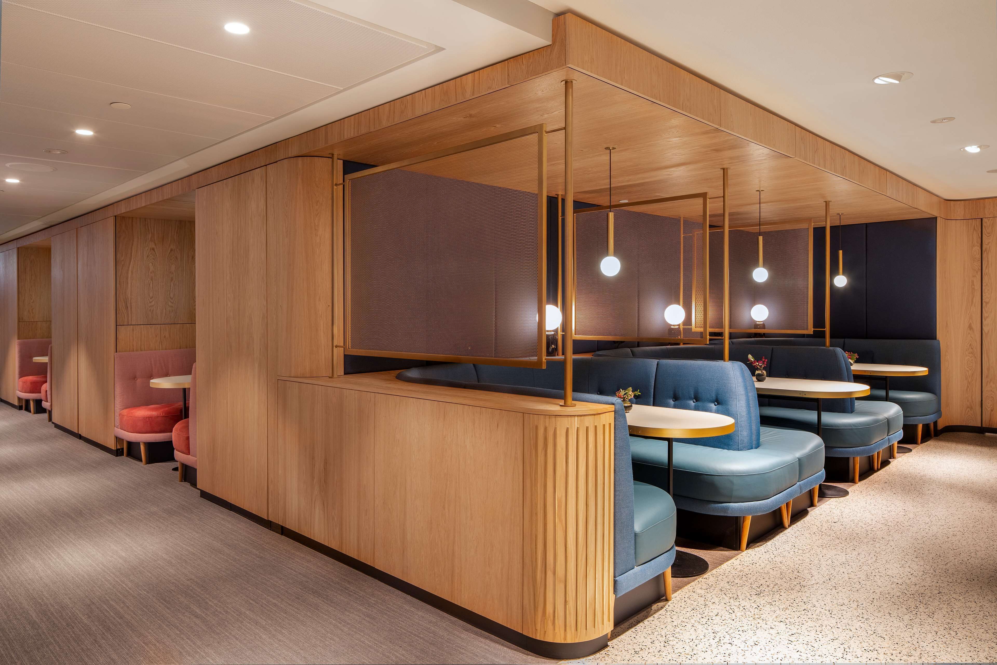 Ein modernes Restaurant mit Holzwandverkleidung, blauen Sitzgelegenheiten und Pendelleuchten.