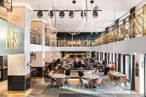 Un restaurante moderno con varias zonas de comedor, un bar y una cocina a la vista.