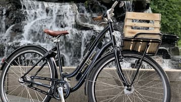 Una bicicleta con una cesta de madera en la parte delantera, estacionada frente a una cascada.