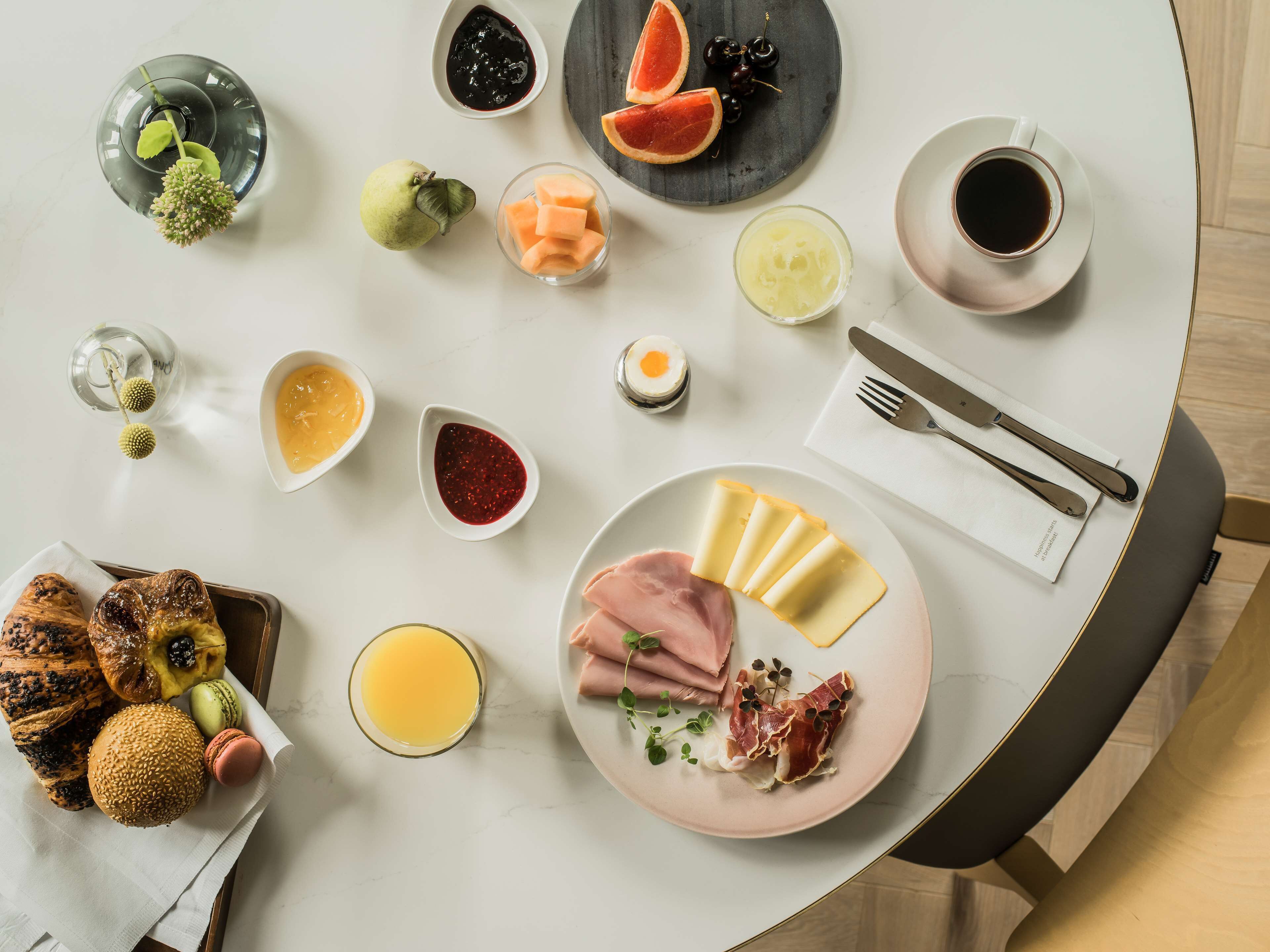 Una mesa de desayuno con diversas opciones de comida, como tostadas, pasteles, fruta y bebidas.